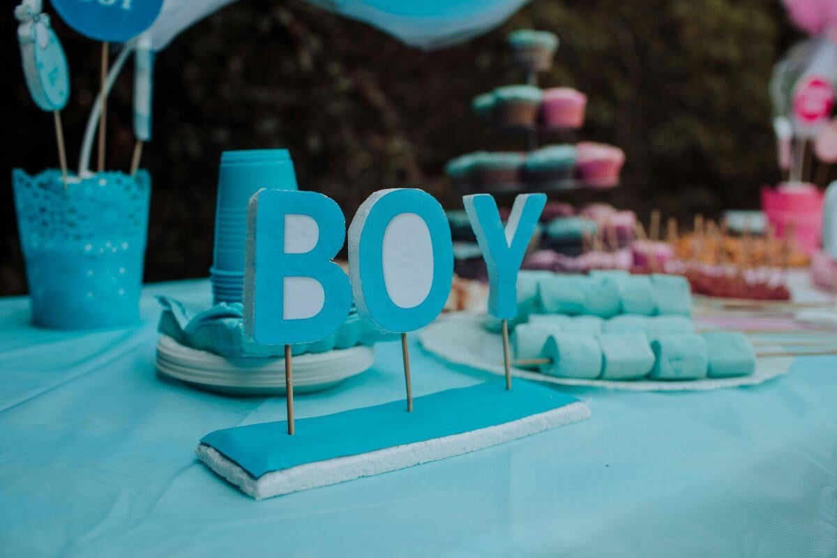 1. Petrecere gender reveal - masa festiva, pahare, tacamuri farfurii, deserturi, banner, baiat